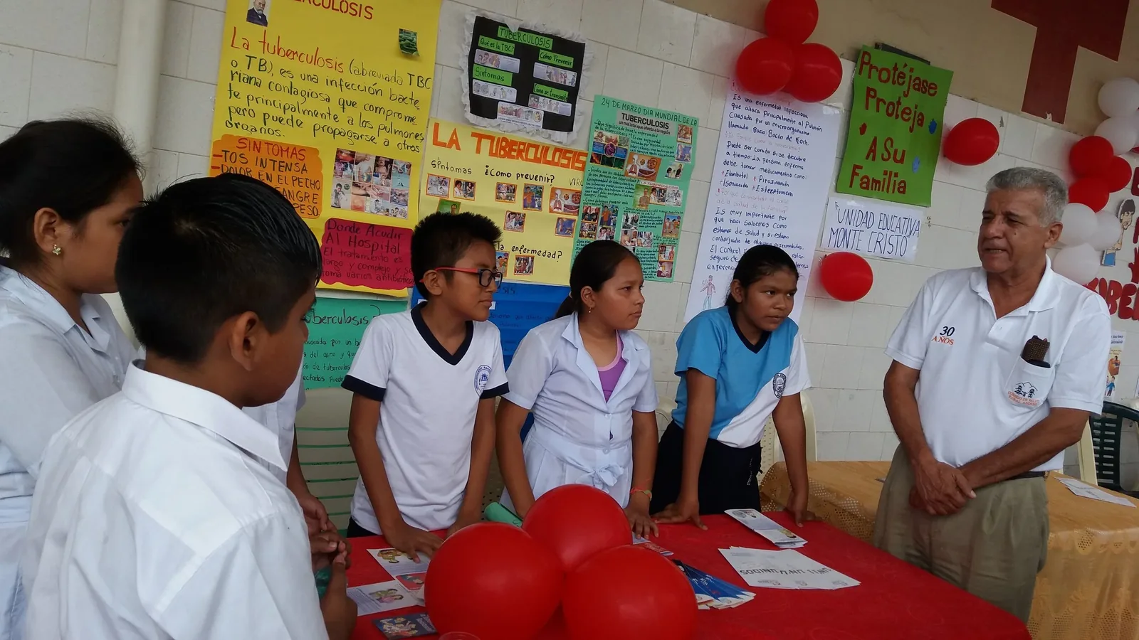 Students present health education posters on tuberculosis at a community event